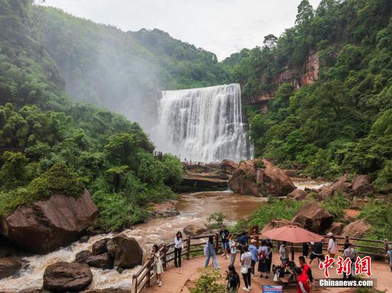 5月27日，游客在赤水丹霞旅游区·赤水大瀑布前游玩拍照。